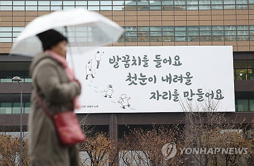 기온이 영상권을 회복한 27일 오전 서울 종로구 광화문광장 인근에 비가 내리자 시민이 비를 피하고 있다. [연합뉴스]